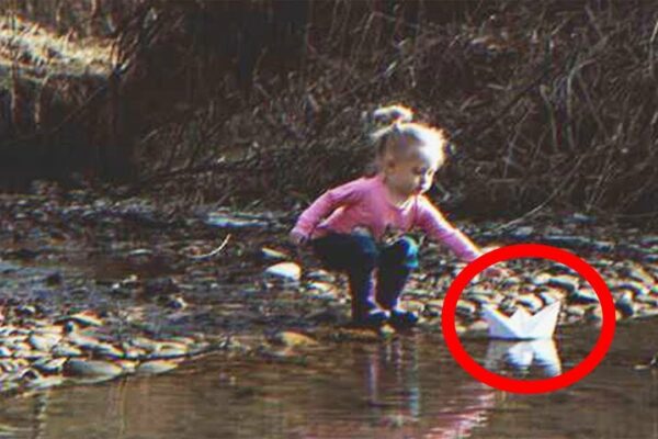 Fetița găsește o barcă de hârtie care navighează pe râu pe care este scris „Ajută-ne”.