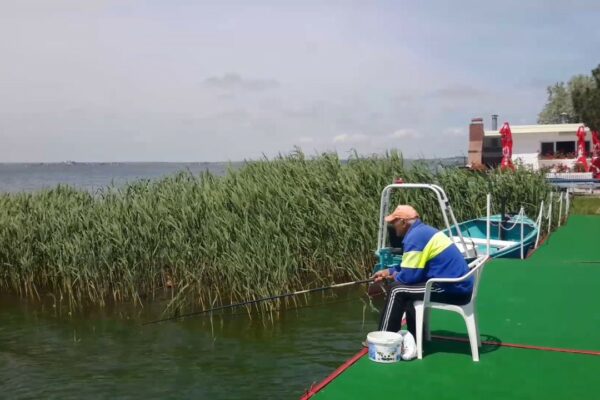 Club nautic pe partea interioară a plajei Mamaia, România.  Omul care pescuiește.  Cazare pe malul apei.