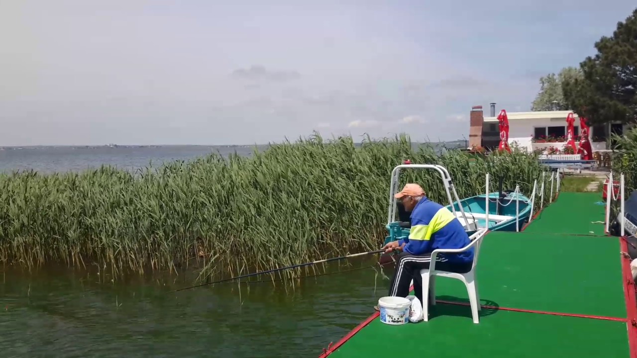 Club nautic pe partea interioară a plajei Mamaia, România.  Omul care pescuiește.  Cazare pe malul apei.